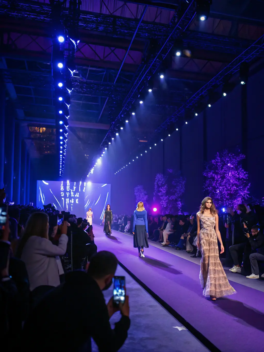 An image of a community event featuring a silk fashion show, with models wearing traditional and modern silk garments on a small stage, audience applauding.